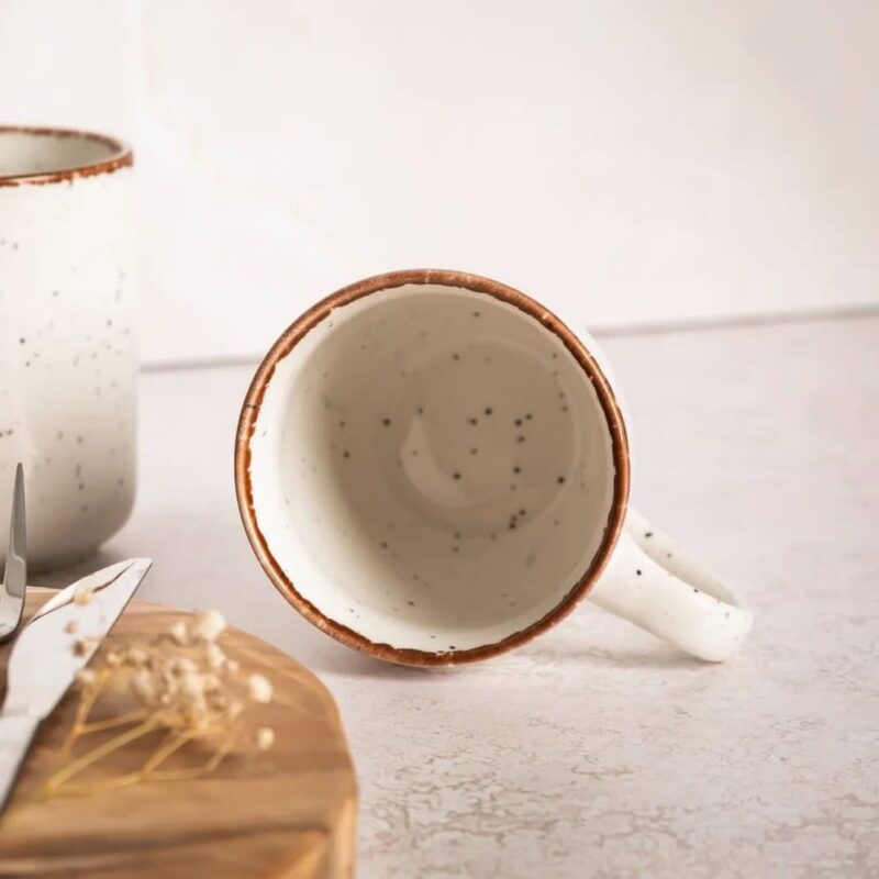 Czarna ceramiczna filiżanka z brązową krawędzią na białym tle, idealna do kawy lub herbaty, wpisująca się w rusticzną estetykę domowego zacisza.