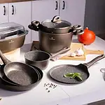 Trwałe garnki i patelnie VALDINEX na kuchennym blacie, z drewna i warzywami, nowoczesne naczynia kuchenne.