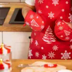 Czerwone rękawice kuchenne z motywami świątecznymi, śnieżynkami i choinkami, idealne na Boże Narodzenie, w kuchni, przy pieczeniu i dekoracji świątecznej atmosfery.