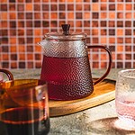 Słój z herbatą na drewnianym podkładce z kolorowym tłem, idealny do relaksu i cieszenia się chwilą, domowy sposób na aromatyczne napoje i sprzyjającą atmosferę w domu.
