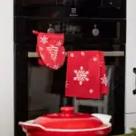 Ciepła rękawica i ręcznik kuchenny na drążku w kuchni z motywem śnieżynki, idealne na świąteczny wystrój i funkcjonalność w domu.