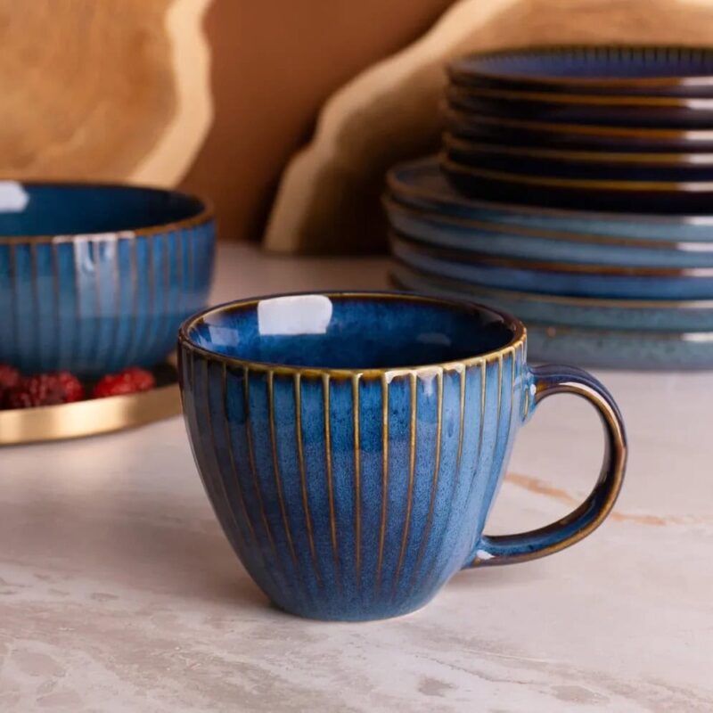 Ceramiczna filiżanka w odcieniach niebieskiego z złotymi pasami, idealna do kawy lub herbaty, elegancka zastawa stołowa od Domowego Zakątka.