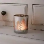 Lampka dekoracyjna z motywem choinek na świece w domu, dodająca ciepłego, świątecznego klimatu i atmosfery zimowych wieczorów. Idealna do wnętrz w stylu boho i rustykalnym, przy kominku lub na stole.