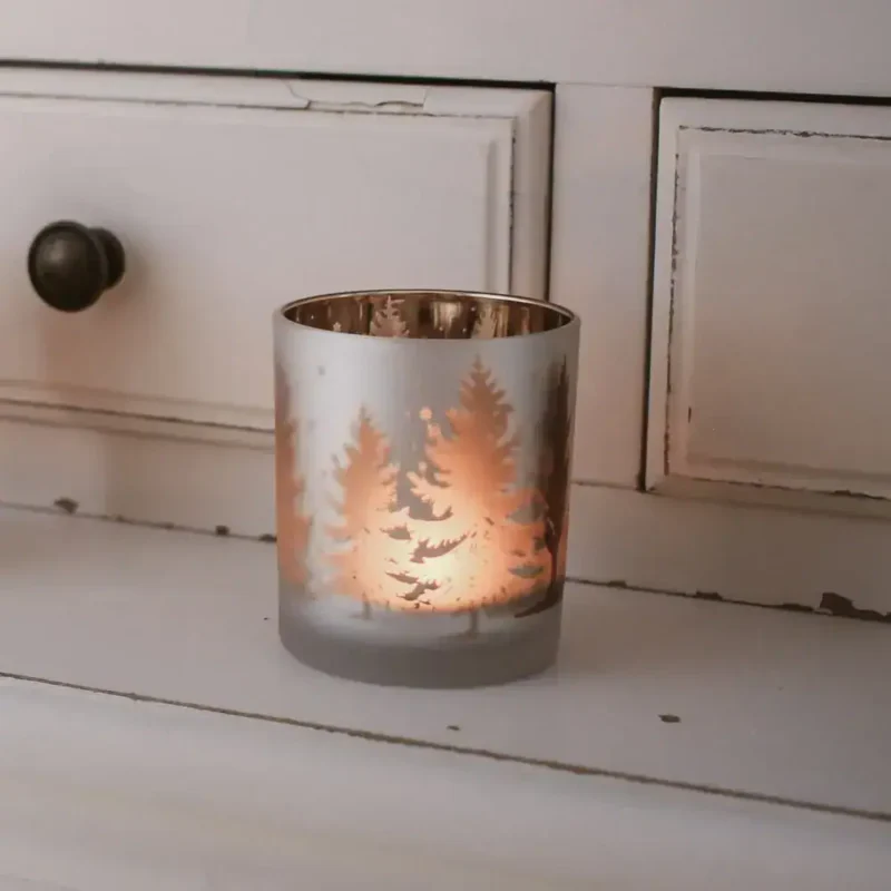 Lampka dekoracyjna z motywem choinek na świece w domu, dodająca ciepłego, świątecznego klimatu i atmosfery zimowych wieczorów. Idealna do wnętrz w stylu boho i rustykalnym, przy kominku lub na stole.