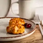 Pieczone kotlety z kurczaka z rożkiem na talerzu, podane z czerwonymi jagodami, rustykalny drewniany blat, inspirowane domowym jedzeniem, zdrowe i smaczne posiłki.