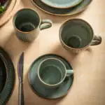 Porcelanowe kubki i talerze w stylu rustykalnym z unikalnym zdobieniem, idealne do kawy i herbaty, tworząc przytulny klimat w domowym zakątku.