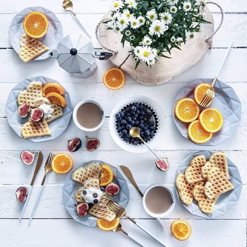 Orazędzi z oranżadą i owocami, na białym tle, wspólny brunch z domowymi goframi, świeżymi jagodami, figami i kwiatami na decorative wooden tray, w stylu skandynawskim, idealny na śniadanie lub spotkanie przy kawie.