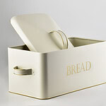 Metalowa skrzynka na chleb w jasnym odcieniu z ozdobnym złotym napisem "BREAD" idealna do przechowywania pieczywa w domu. Funkcjonalna i elegancka, świetnie pasuje do nowoczesnej kuchni i stylowych wnętrz.