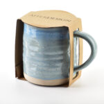 Fiber ceramic mug with cardboard packaging, handmade pottery mug in speckled light blue glaze, perfect for home decor and kitchen use, from Domowy Zakątek.