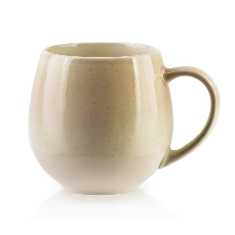 Cieplej kubek ceramiczny w odcieniu beżu, idealny na herbatę lub kawę, w domowym zaciszu.