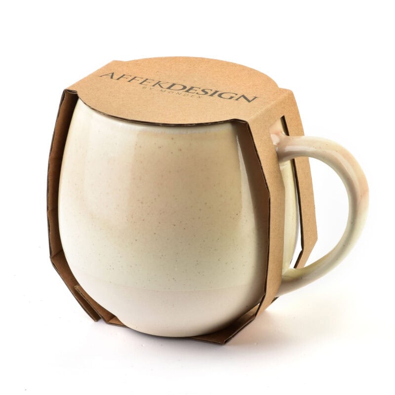 Ckeditor-image-alt-text: Ceramiczna filiżanka z herbatą, opakowana w ekologiczne papierowe etui, idealna do domowego relaksu i kawy na co dzień.