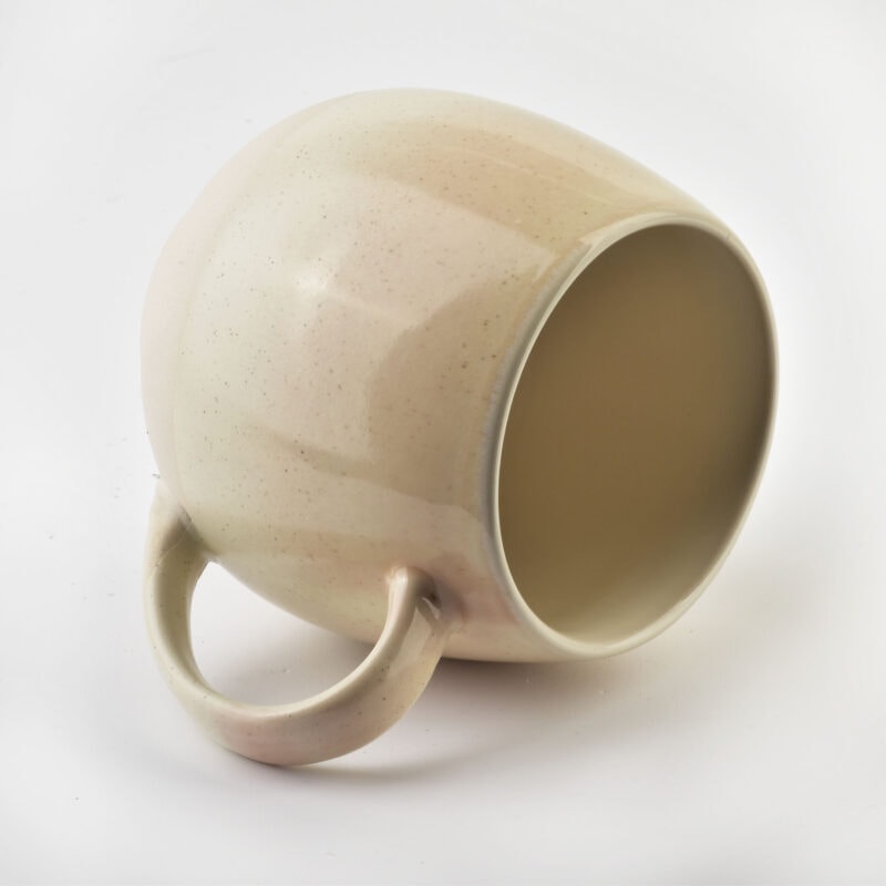 Ceramiczna filiżanka z jasnym, subtelnym wykończeniem, idealna na kawę lub herbatę do domu lub biura. Tradycyjny design z wygodnym uchwytem, w kolorze beżowym z delikatnym połyskiem, wpisujący się w styl domowego zacisza.