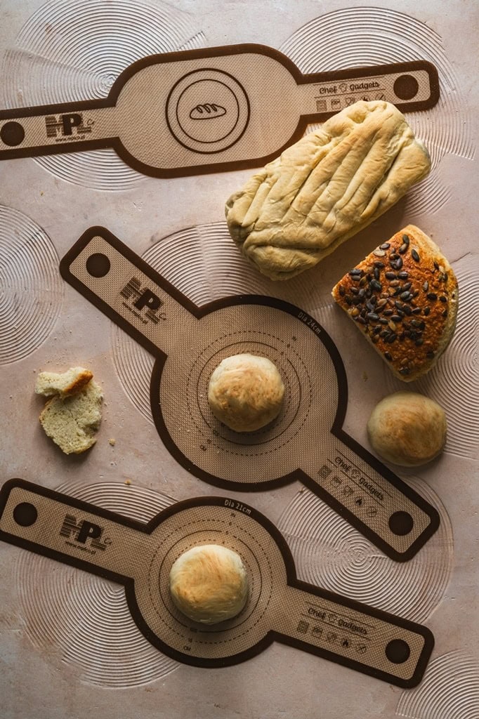 Miara do pieczenia i formowania ciasta na blacie kuchennym, na tle rozwałkowanego ciasta, rękawa cukierniczego i ciastek, w kuchni domowej, wygodne narzędzia kuchenne, pies do wypieków, melamina i silikon.