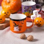 Kolorowa kubek Halloween z motywem ducha i napisem Boo na Halloween, idealny na sezon jesienno-zimowy, ozdobiony dynią i cukierkami, doskonały na kawę lub herbatę w domu lub pracy.