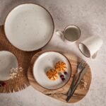 Białe ceramiczne naczynia z brązową obwódką, zestaw do serwowania na drewianym półmisku, idealne do domowego użytku i dekoracji stołu, z kawą, herbatą, czy deserami, dodają uroku i elegancji.