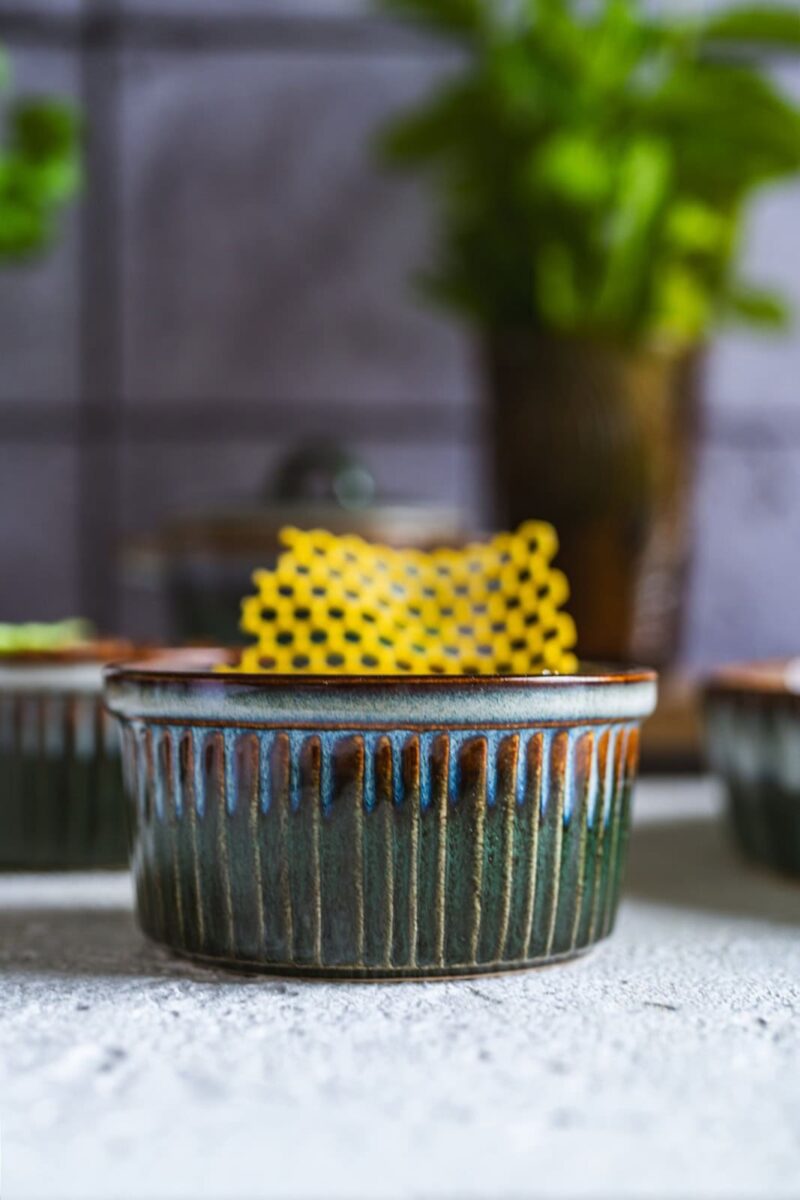 Nowoczesne ceramiczne naczynie do pieczenia z ręcznie zdobionym wzorem i żółtym ręcznikiem kuchennym w tle, idealne do domowych wypieków i serwowania potraw.