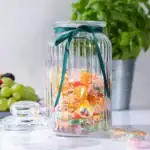 Kolorowe cukierki w ozdobnym szklanym słoju z tealowską wstążką, idealne na słodkie przekąski w domu, element dekoracji i praktyczna ozdoba kuchni, Domowy Zakątek, wystrój wnętrz.