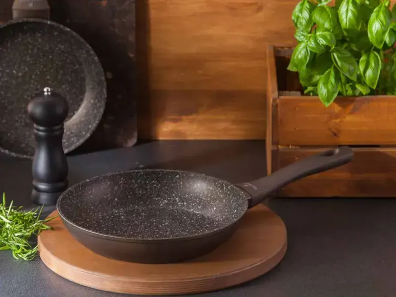 Nowa patelnia z powłoką non-stick na drewnianej podstawce, idealna do domowego gotowania i smażenia, nowoczesny design i funkcjonalność, idealna do kuchni w stylu domowym zakątku.