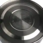 Stalowa pokrywa do garnków i patelni, wysokiej jakości naczynie kuchenne, emblem z oznaczeniem bezpieczeństwa i trwałości, nowoczesny design, idealne do użytku codziennego w domu, odporne na zarysowania i korozję.