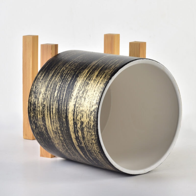 Czarna ceramiczna filiżanka z złotym wzorem, idealna do kawy lub herbaty, ustawiona na drewnianym podstawku, elegancki i nowoczesny design.