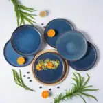 Eleganckie niebieskie talerze ceramiczne na stół, dekorowane owocami i zielonymi gałązkami, idealne do serwowania potraw na specjalne okazje.