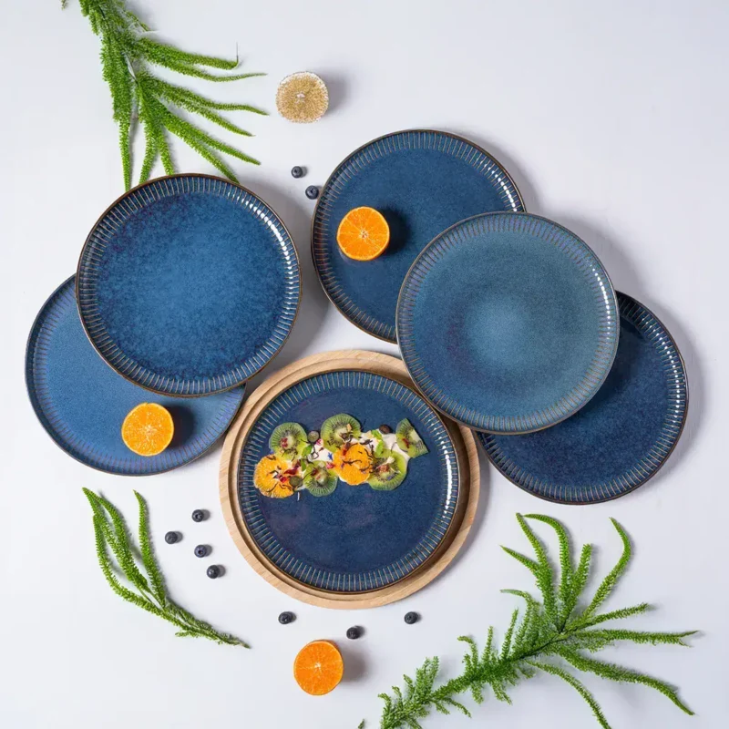 Eleganckie niebieskie talerze ceramiczne na stół, dekorowane owocami i zielonymi gałązkami, idealne do serwowania potraw na specjalne okazje.
