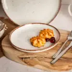 Delikatne kawałki panierowanego sera na eleganckim talerzu z borówkami, idealne na domowe przekąski i śniadania, element wystroju kuchni w stylu rustic, wymiary około 20 cm, z ceramiki.