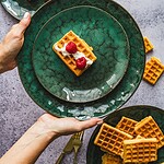 Waffle z bitą śmietaną i malinami na zielonym talerzu, deser domowy, słodka przekąska, sezonowe owoce, domowy zakątek, eleganckie nakrycie, komfortowe jedzenie.