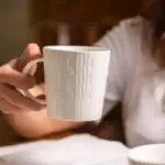 Czysta biała filiżanka z delikatnym wzorem na ceramicznym kubku, idealna do kawy lub herbaty domowej roboty, elegancka zastawa ceramiczna, wysoka jakość, stylowe akcesoria kuchenne.