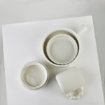 Biały ceramiczny zestaw filiżanek i miseczek na białej powierzchni, idealny do kawy i herbaty w domowym zaciszu, eleganckie naczynia do codziennych i okazjonalnych posiłków w domu, Domowy Zakątek.