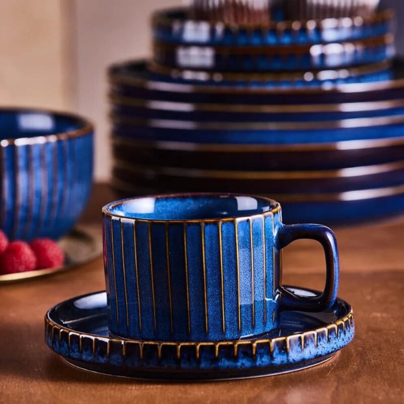 Ceramiczna filiżanka z talerzykiem w eleganckim niebieskim kolorze z złotymi pasami, zestaw do kawy lub herbaty, dekoracyjny element wnętrza domu, wysokiej jakości porcelana Domowy Zakątek.
