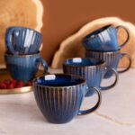 Eleganckie filiżanki ceramiczne w głębokim odcieniu niebieskiego z złotymi paskami, idealne na kawę lub herbatę, dla miłośników stylowego domu i wyjątkowego designu.