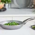 Wnętrze nowoczesnej kuchni z patelnią na indukcję i świeżymi zielonymi warzywami.
