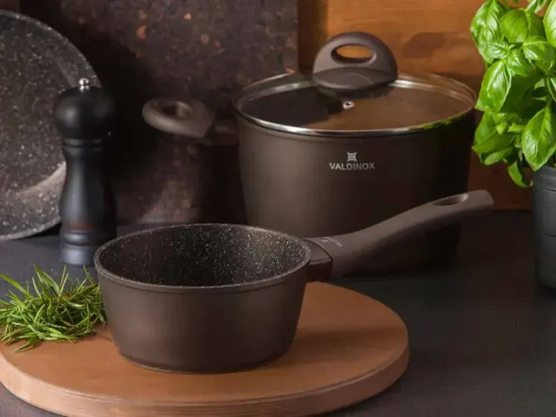 Solidny garnek kuchenny z powłoką non-stick, idealny do smażenia i gotowania, na tle nowoczesnej kuchni z akcesoriami kuchennymi i roślinami, zapewniającej funkcjonalność i nowoczesny styl.