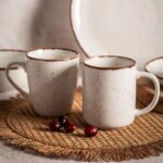 Ceramiczne kubki w stylu rustykalnym, białe z brązową obwódką, zestaw do kawy i herbaty, naturalne akcesoria kuchenne, stylowe naczynia domowe.