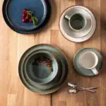 Ceramiczne naczynia do kawy i herbaty, zastawa stołowa z ozdobnym złotym wykończeniem, filiżanki, talerzyki teowe, kawa i orzechy na drewnianym stole, elegancki zestaw do kawiarni domowej Domowy Zakątek.