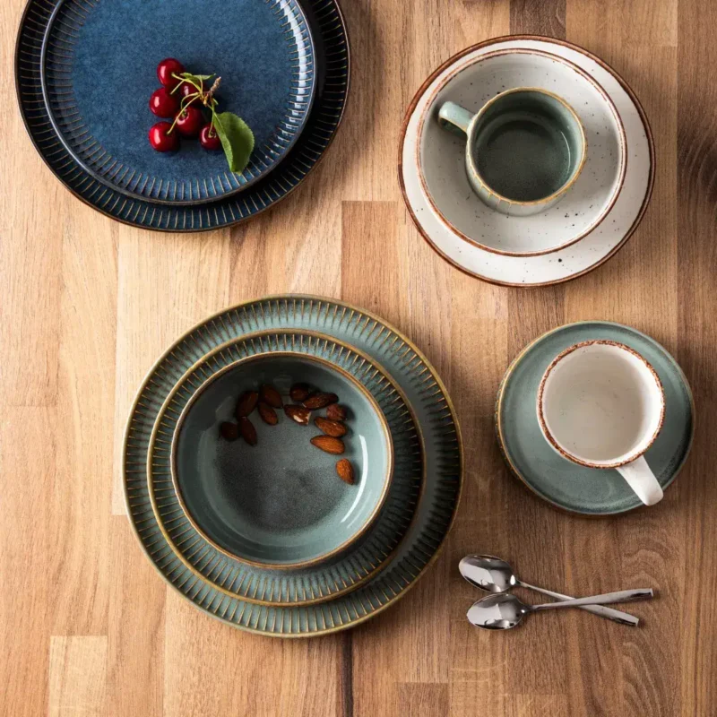 Ceramiczne naczynia do kawy i herbaty, zastawa stołowa z ozdobnym złotym wykończeniem, filiżanki, talerzyki teowe, kawa i orzechy na drewnianym stole, elegancki zestaw do kawiarni domowej Domowy Zakątek.
