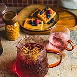 Kreatywny dzbanek i filiżanki z herbatą ziołową, obok talerz z wafelkami i świeżymi jagodami, na rustykalnym stole, promujące naturalne napoje i domową atmosferę, idealne na relaks.
