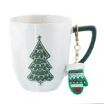 Stylowy kubek z dekoracją świąteczną i bożonarodzeniową rękawiczką na kluczu, idealny do domowego zakątka w okresie świątecznym, podkreślający świąteczny klimat i elegancję.