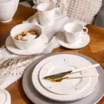 Ciekawiasta zastawa stołowa w świątecznym stylu, zestaw porcelany z złotymi akcentami, filiżanki i talerzyki na Boże Narodzenie, elegancka zastawa na świąteczny stół, dekoracyjny zestaw na bożonarodzeniowy stół.