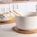 Niska biała miska na drewnianej podstawce w kuchni, dekoracyjny stół z filiżankami i czajnikiem, domowa atmosfera, akcesoria kuchenne, styl skandynawski, nakrycie stołu, elegancka aranżacja kuchni, Domowy Zakątek.