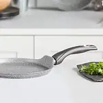 Ogrodzona patelnia ceramiczna na białym blacie w nowoczesnej kuchni, idealna do smażenia i przygotowywania zdrowych posiłków, trwała i łatwa w czyszczeniu, niezawodny wybór dla każdego domu.
