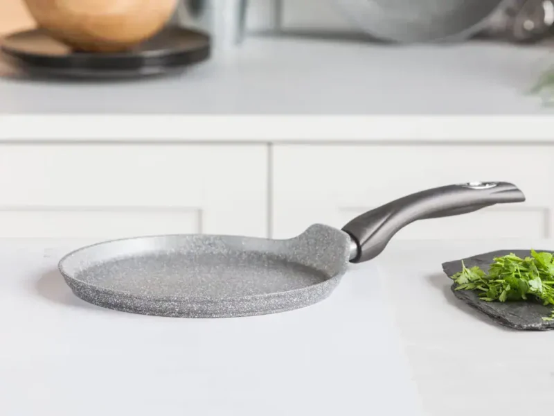 Ogrodzona patelnia ceramiczna na białym blacie w nowoczesnej kuchni, idealna do smażenia i przygotowywania zdrowych posiłków, trwała i łatwa w czyszczeniu, niezawodny wybór dla każdego domu.