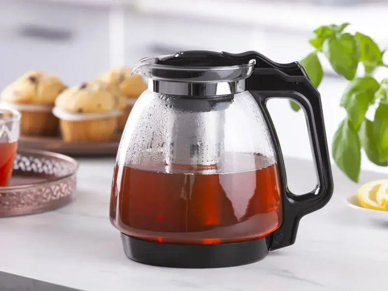 Sokowirówka w stylu retro na jasnym stole z kawałkami cytryny i świeżą bazylią w tle, idealna do przygotowania soku z owoców i warzyw, funkcjonalny i elegancki sprzęt kuchenny Domowy Zakątek.