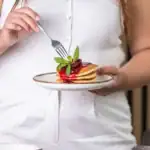 Pierwszy plan na danie z naleśników z owocami i miętą, elegancko podany na białym talerzu. Idealny deser lub śniadanie, atrakcyjny wizualnie i smakowo, wpisujący się w trend zdrowych i estetycznych posiłków.