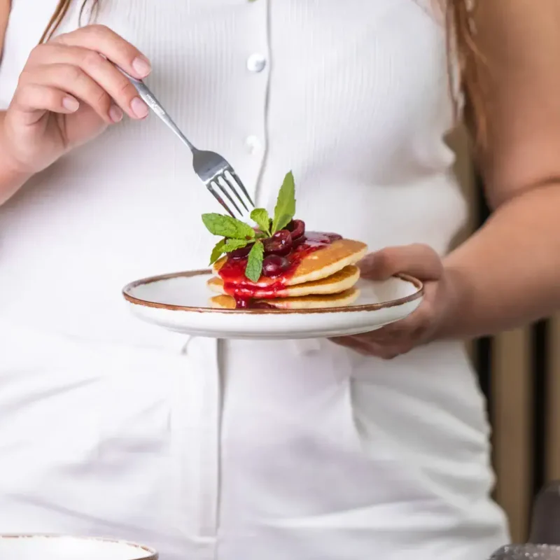 Pierwszy plan na danie z naleśników z owocami i miętą, elegancko podany na białym talerzu. Idealny deser lub śniadanie, atrakcyjny wizualnie i smakowo, wpisujący się w trend zdrowych i estetycznych posiłków.