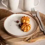 Delikatne kotleciki drobiowe na talerzu z czarnymi porzeczkami, podane na naturalnym drewnianym stole, w rustykalnym stylu, idealne do domowej kuchni, postawione w stylu farmhouse, polskie danie.