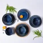 Ceramiczne naczynia w odcieniach niebieskiego na białym tle, elementy dekoracyjne i naturalne dodatki, idealne do domowego wystroju i serwowania potraw.