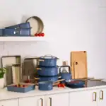 Blaszane i ceramiczne naczynia kuchenne w kolorze granatowym, idealne do gotowania i dekoracji w kuchni domowego zakątka. W Komplet wchodzi patelnia, garnek, rondel i naczynia do pieczenia.
